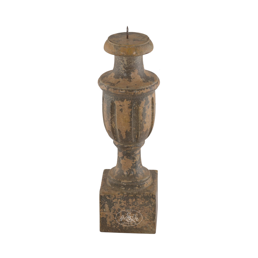 A wooden carved candle stand with floral patterns and a distressed antique finish in muted tones.