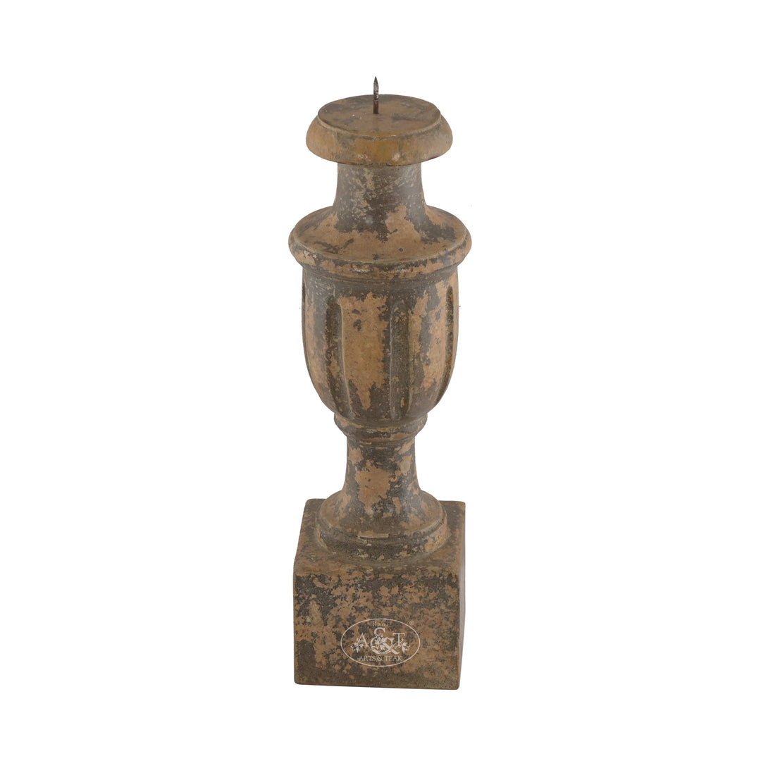 A wooden carved candle stand with floral patterns and a distressed antique finish in muted tones.