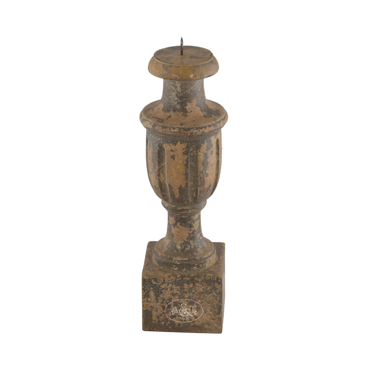 A wooden carved candle stand with floral patterns and a distressed antique finish in muted tones.