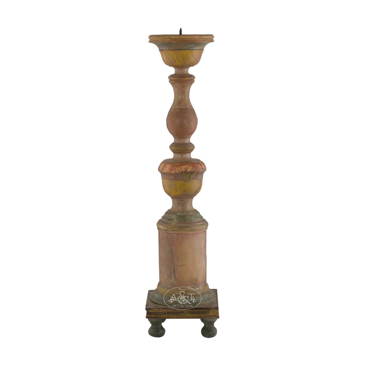 A tall wooden carved candle stand with a multicolored distressed finish, featuring an ornate, antique-style design with a pedestal base and elegant legs.