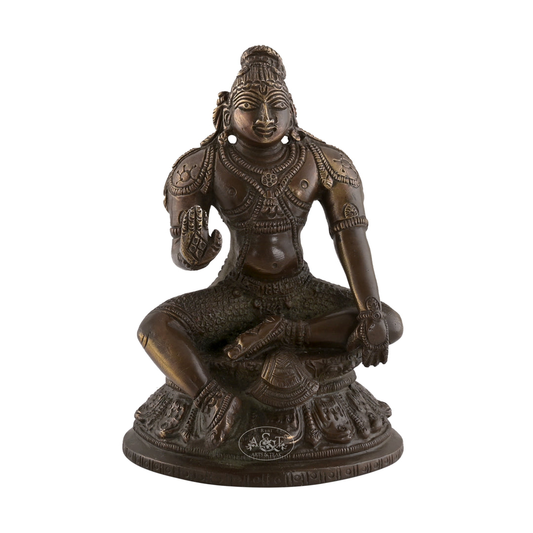 A bronze-colored brass statue of Lord Krishna seated in a calm posture on a base.