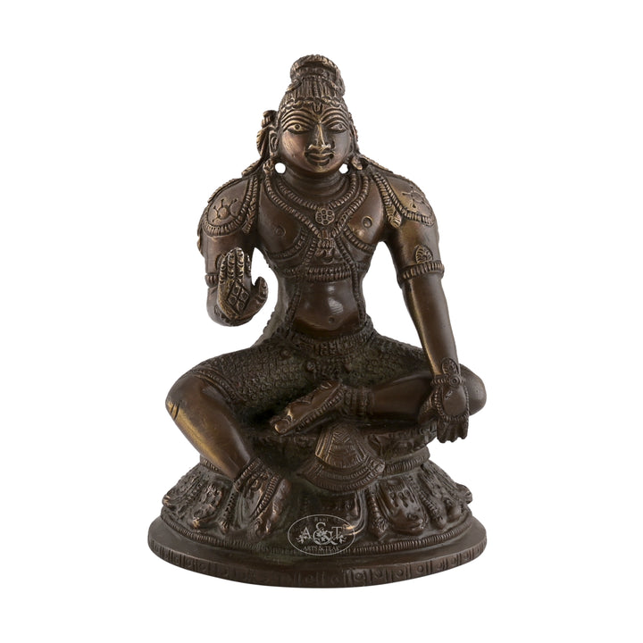 A bronze-colored brass statue of Lord Krishna seated in a calm posture on a base.