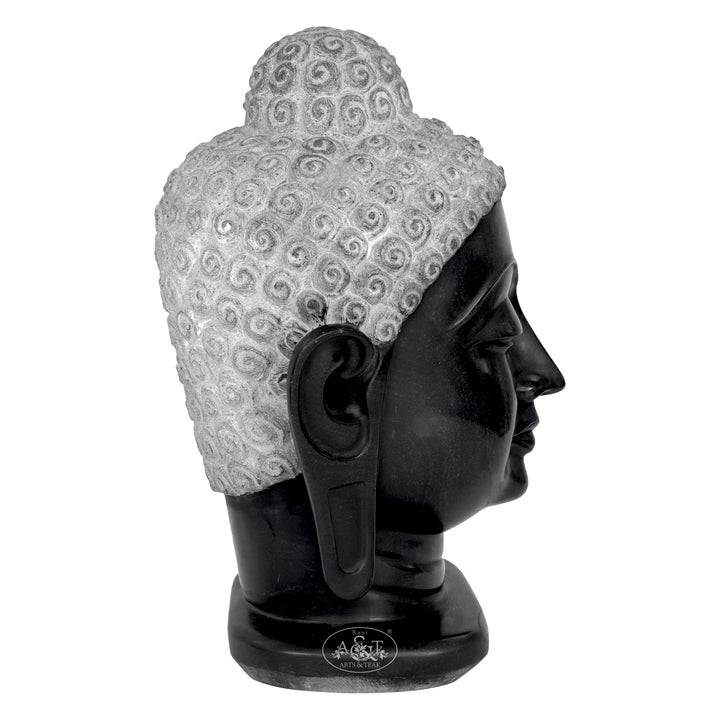 Black marble Buddha head sculpture with intricate patterns on a white background