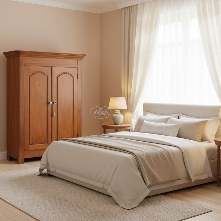 Neatly made bed in a bedroom with wooden wardrobe and lamp.